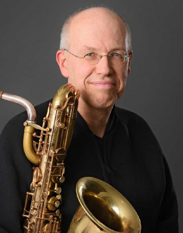 Auf dem Foto sieht man das Halbportrait des Saxofonisten Edgar Herzog . Er lächelt in die Kamera. Vor sich hält er ein Tenorsaxofon.